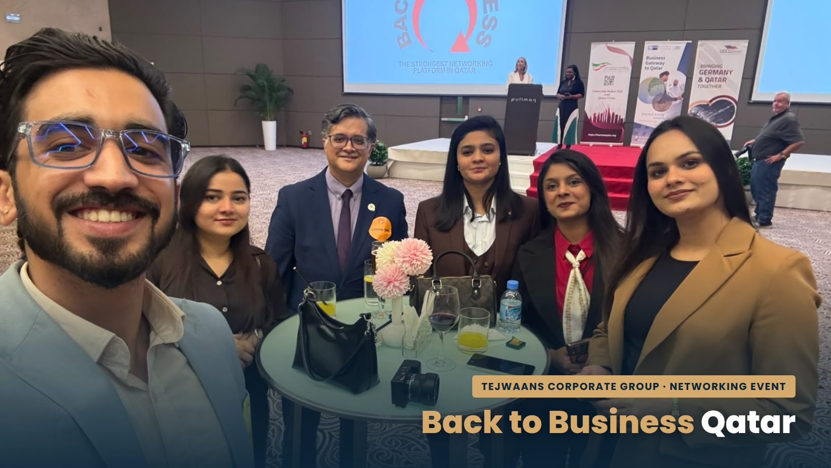 Tejwaans Corporate Group team selfie at the Back to Business networking event in Qatar, with the event stage and screen behind